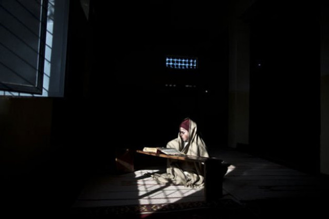 a student sits on a spot of light as he is wrapped in a shawl to warm himself while reading verses of the quran prior to a class a student sits on a spot of light as he is wrapped in a shawl to warm himself while reading verses of the quran prior to a class