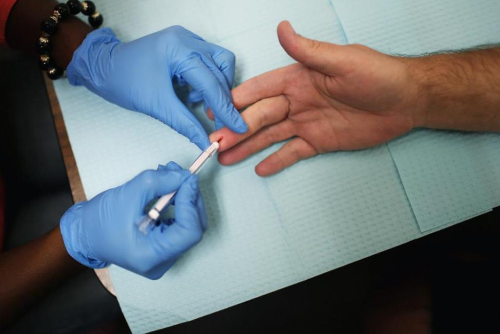 a health educator uses a syringe to take a drop of blood from a man 039 s finger to conducting an hiv test photo afp