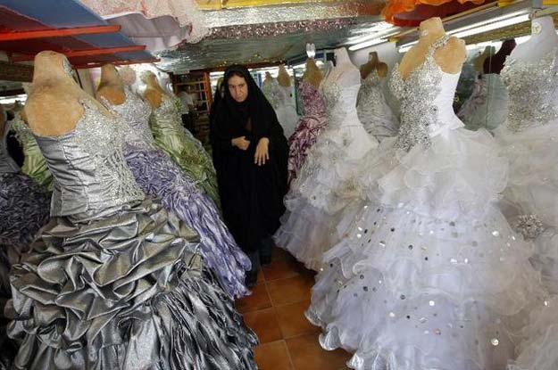 an iranian woman walks past gowns and wedding dresses at a shop in islamshahr 50 kms 31 miles southwest of tehran on may 30 2009 photo afp