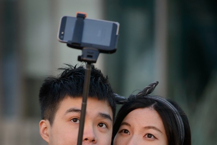 in a photo taken on november 26 2014 a couple use a 039 selfie stick 039 to take a photo at a popular tourist spot in seoul south korea photo afp