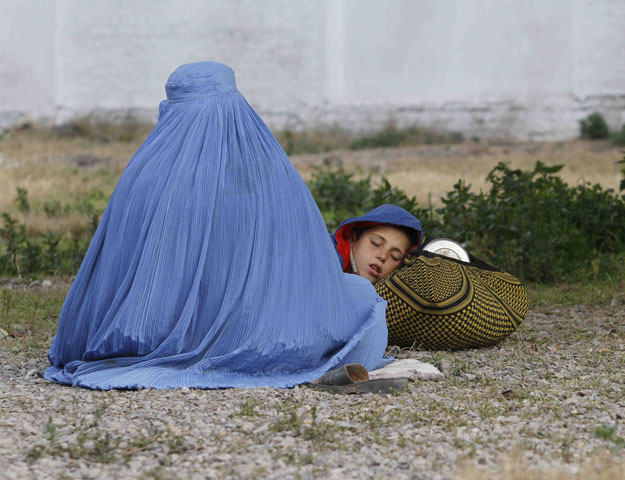 an afghan refugee woman clad in a burqa sits with her sleeping boy as they wait with others to be repatriated to afghanistan at the united nations high commissioner for refugees unhcr office on the outskirts of peshawar february 2 2015 photo reuters