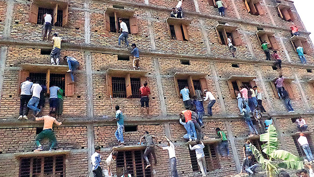 family members and friends climb walls to make answer chits available to those appearing for their class 10 exams at a centre in vaishali bihar photo courtesy hindustan times