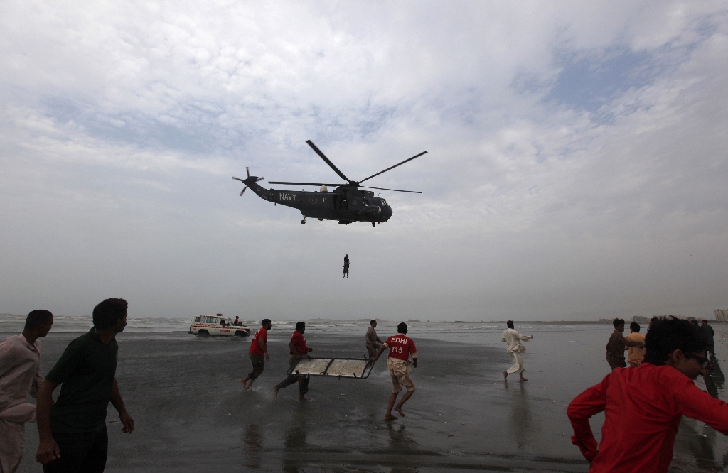 rescue workers in red shirts carry a stretcher as they run to receive the body of a victim who had drowned on wednesday from a pakistan navy helicopter after search rescue operation by the navy at karachi 039 s clifton beach july 31 2014 photo reuters