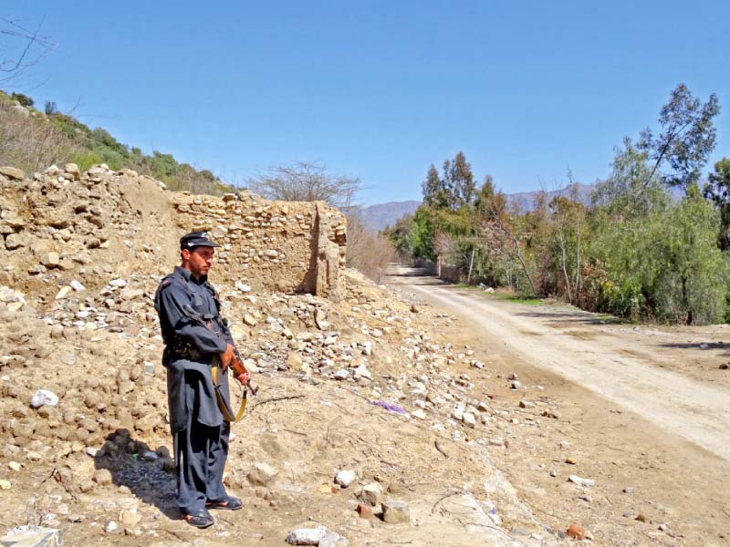 a security official stands guard near the debris of destroyed houses in lower kurram photo iftikhar firdous express