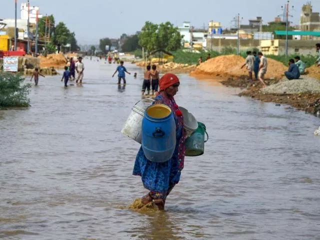 a woman carries drinking water cans as she wades in floodwaters photo getty a woman carries drinking water cans as she wades in floodwaters photo getty