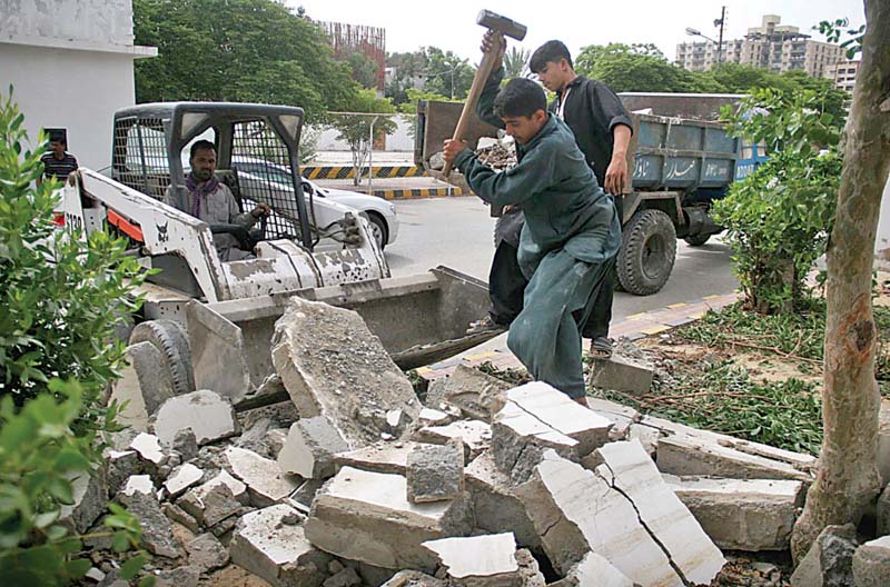 labourers break barriers placed outside the bilawal house although the barricades were finally taken down after seven years the illegal wall on both sides of the median has been left intact photo athar khan express