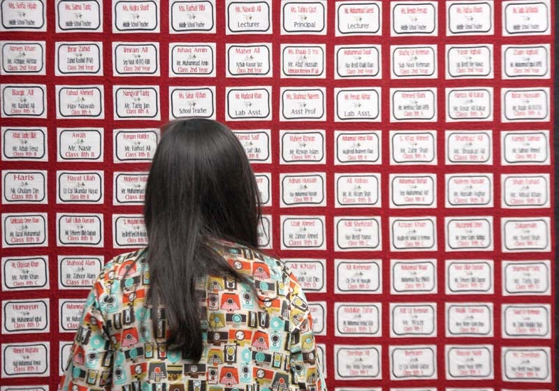 a woman stands in front of a quilt with names of those who passed away in the army public school peshawar attack in december last year photo athar khan express