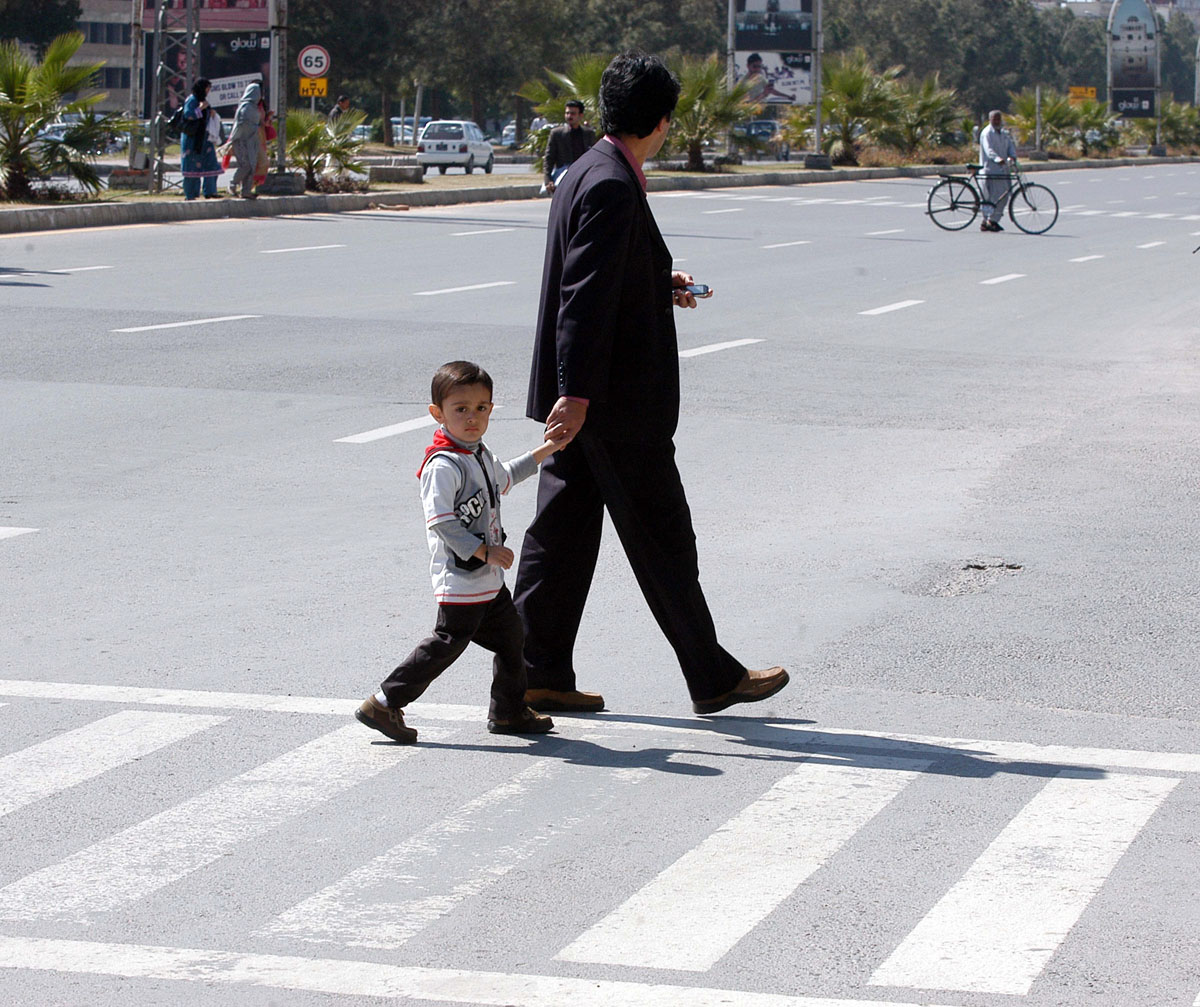 a boy and his father walk over a zebra crossing photo muhammad javaid express