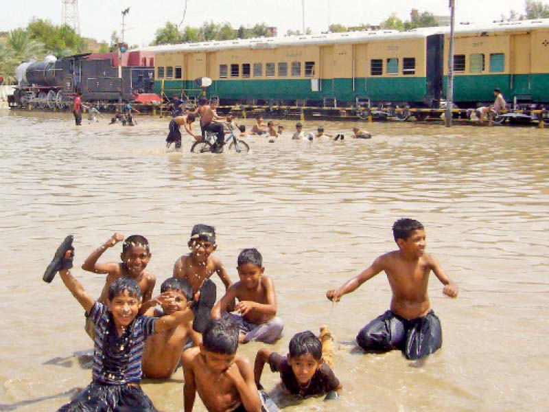 children play in rainwater accumulated in front of the railway station in sukkur heavy rainfall lashed down in parts of upper sindh on monday morning submerging roads and disrupting the electricity supply photo inp