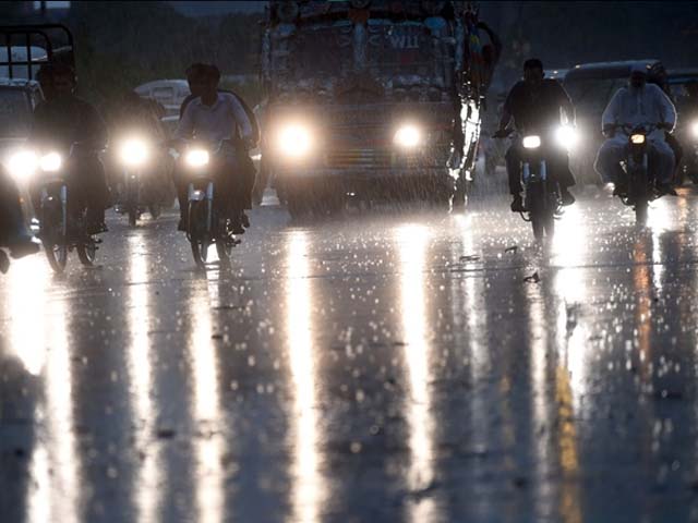 pakistani commuters travel on a street during heavy rain photo getty