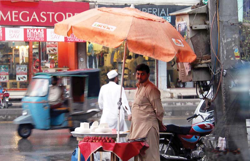 a cheese vendor stands under an umbrella fixed to his stall in saddar photo online