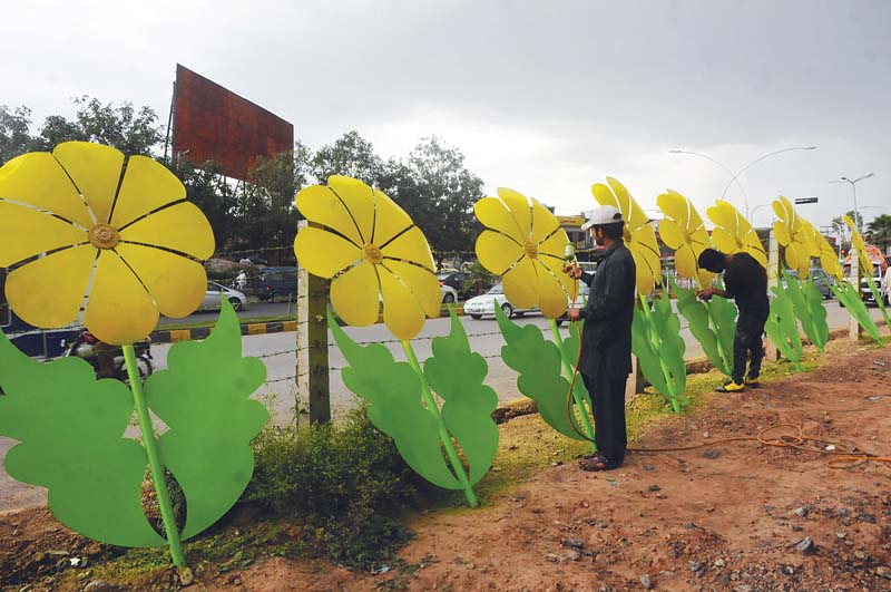 a worker paints artificial flowers along the highway photo waseem nazir express