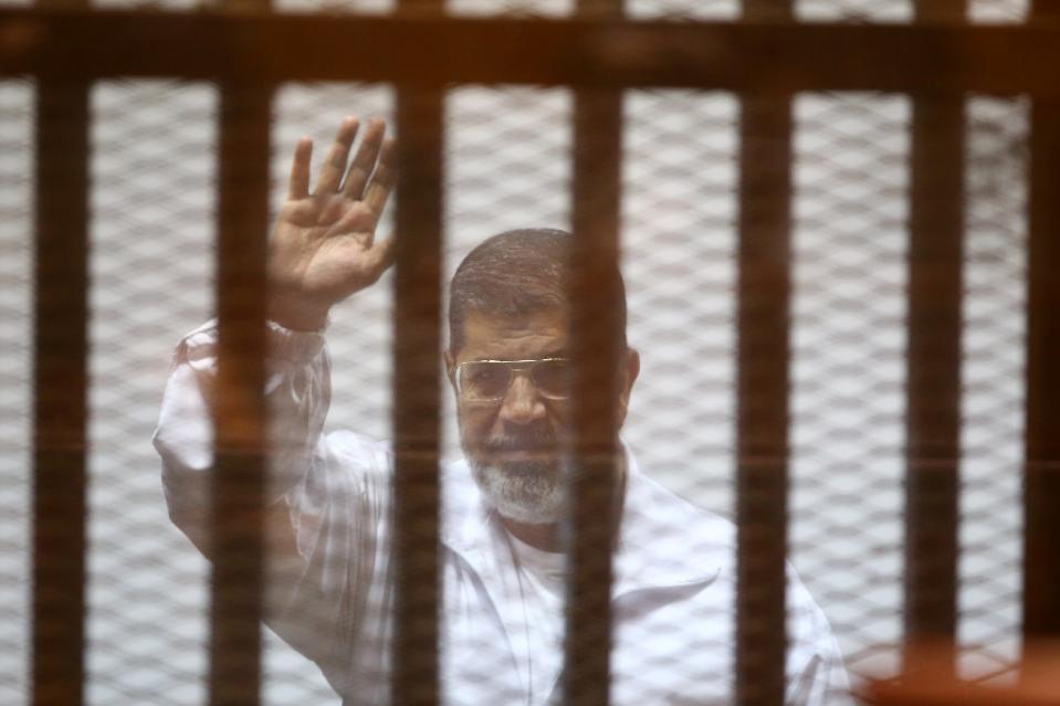 egypt 039 s deposed president mohamed morsi waves inside the defendant s cage during an earlier court hearing at the police academy in cairo on december 7 2014 photo afp