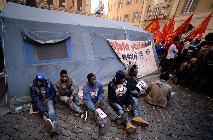 demonstrators holding numbers symbolizing the dead migrants sit during a demonstration in front of the italian parliament in rome 039 s montecitorio square on april 21 2015 photo afp