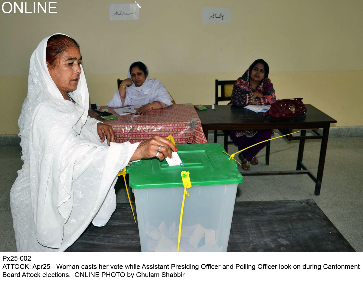 woman casts her vote while assistant presiding officer and polling officer look photo online