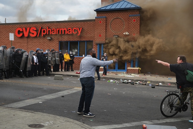 two men argue opposing views as a cvs pharmacy burns at the corner of pennsylvania and north avenues during violent protests following the funeral of freddie gray april 27 2015 in baltimore maryland photo afp