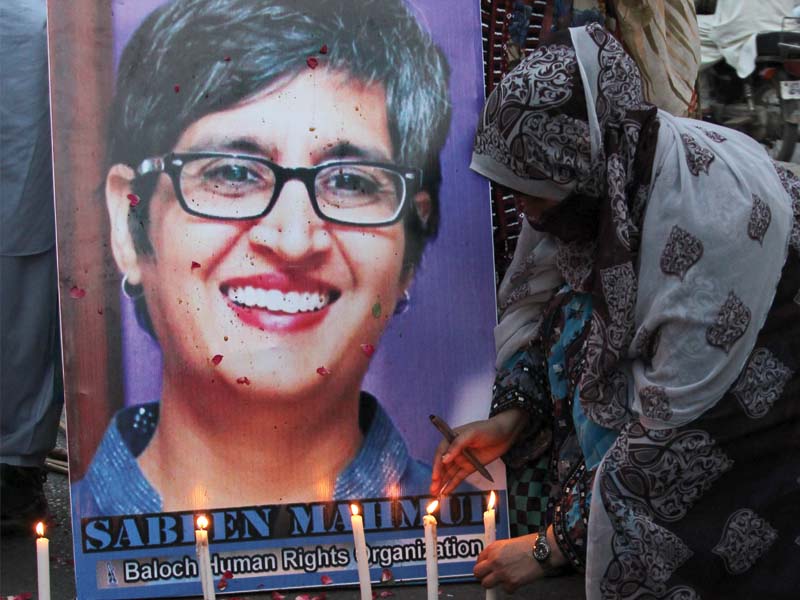 a woman lights a candle in front of a poster of slain activist sabeen mahmud members of civil society gathered at karachi press club on tuesday to protest her murder photo aysha saleem express