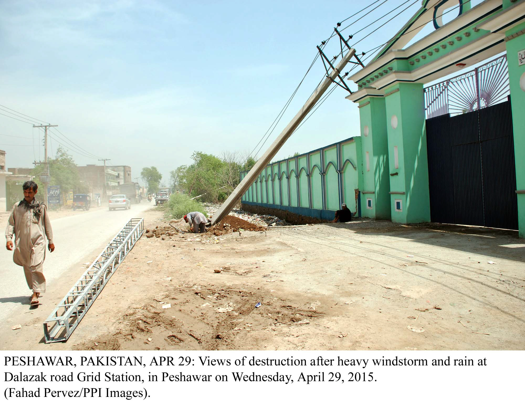 a man walks past a power pole that was knocked over by high winds in peshawar last week photo ppi