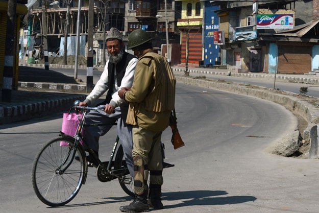 in this file photo an indian paramilitary trooper checks the identity card of a kashmiri cyclist during a curfew in downtown srinagar photo afp