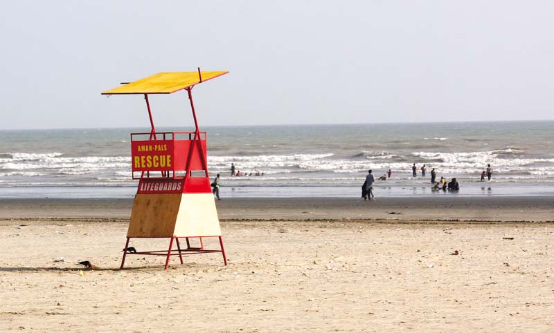 a watch tower stands empty at the beach at sea view while picnickers bathe in the water forty people drowned here last year photo athar khan express