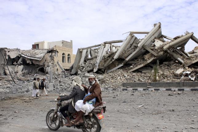 people ride a motorcycle as they pass by a police headquarters destroyed by a saudi led air strike in yemen 039 s northwestern city of saada photo reuters