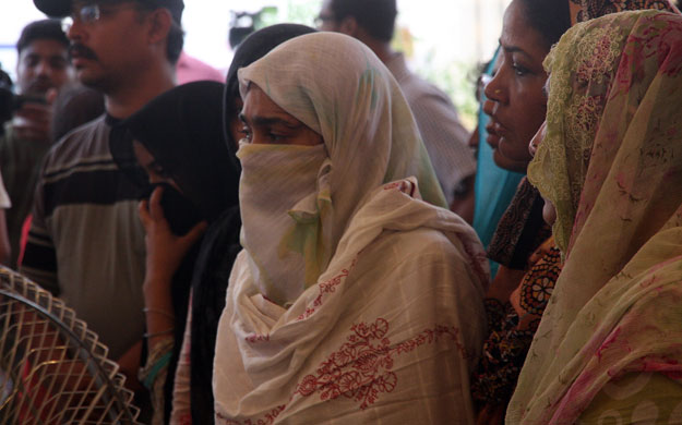 wife of sualat mirza stands by his dead body at their home in gulshan e maymar on tuesday photo athar khan express