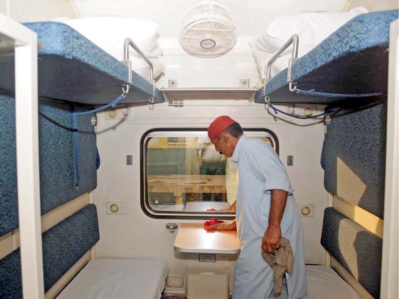 a worker polishes table of a compartment of the green line train in karachi photo express
