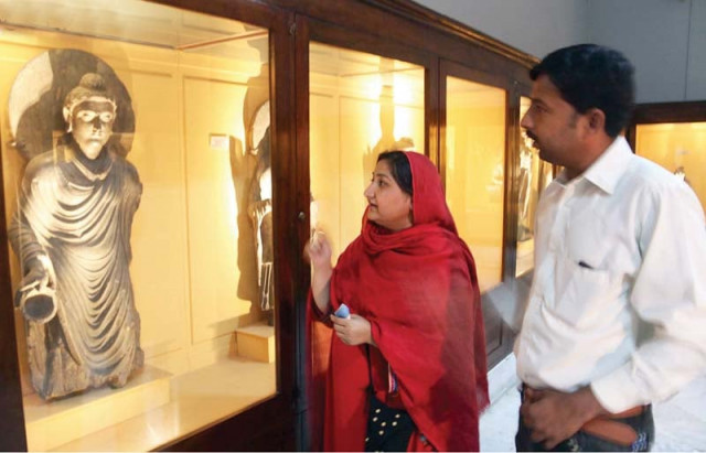 visitors look at a sculpture of buddha in peshawar museum photo online visitors look at a sculpture of buddha in peshawar museum photo online