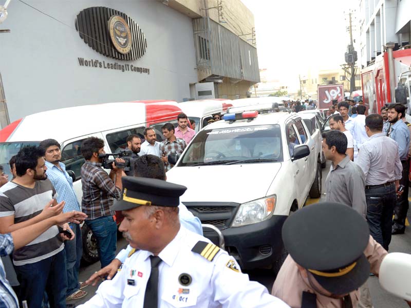 people gather around fia vehicles during a raid on the axact karachi office photo afp