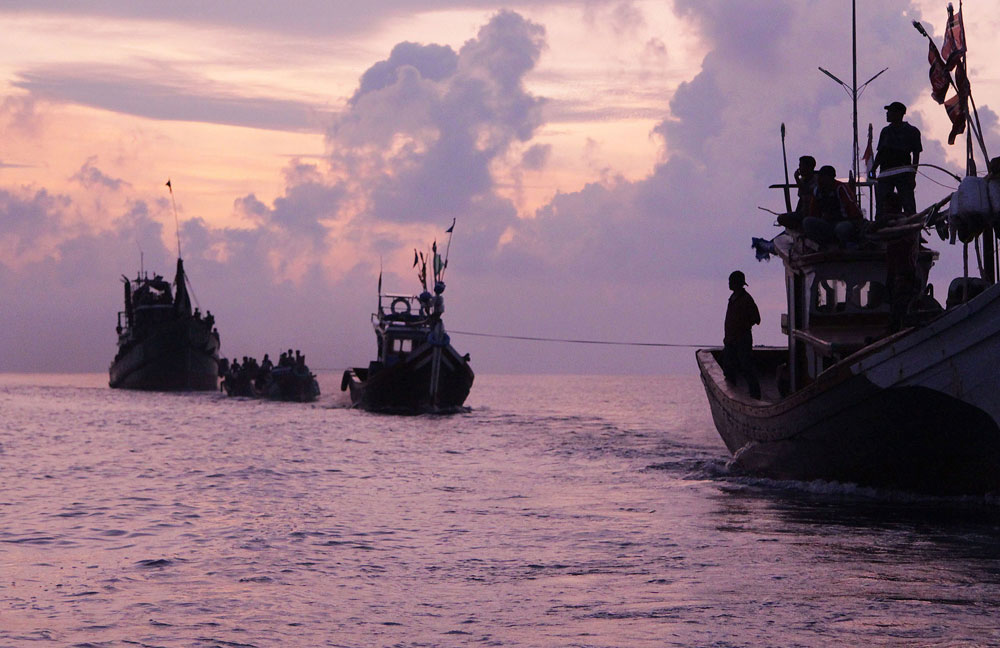 acehnese fishermen r in boats tow a boat of rohingya migrants in their boat l off the coast near the city of geulumpang in indonesia 039 s east aceh district of aceh province at dawn before being rescued on may 20 2015 hundreds of starving boatpeople were rescued off indonesia on may 20 as myanmar for the first time offered to help ease a regional migrant crisis blamed in part on its treatment of the ethnic rohingya minority photo afp