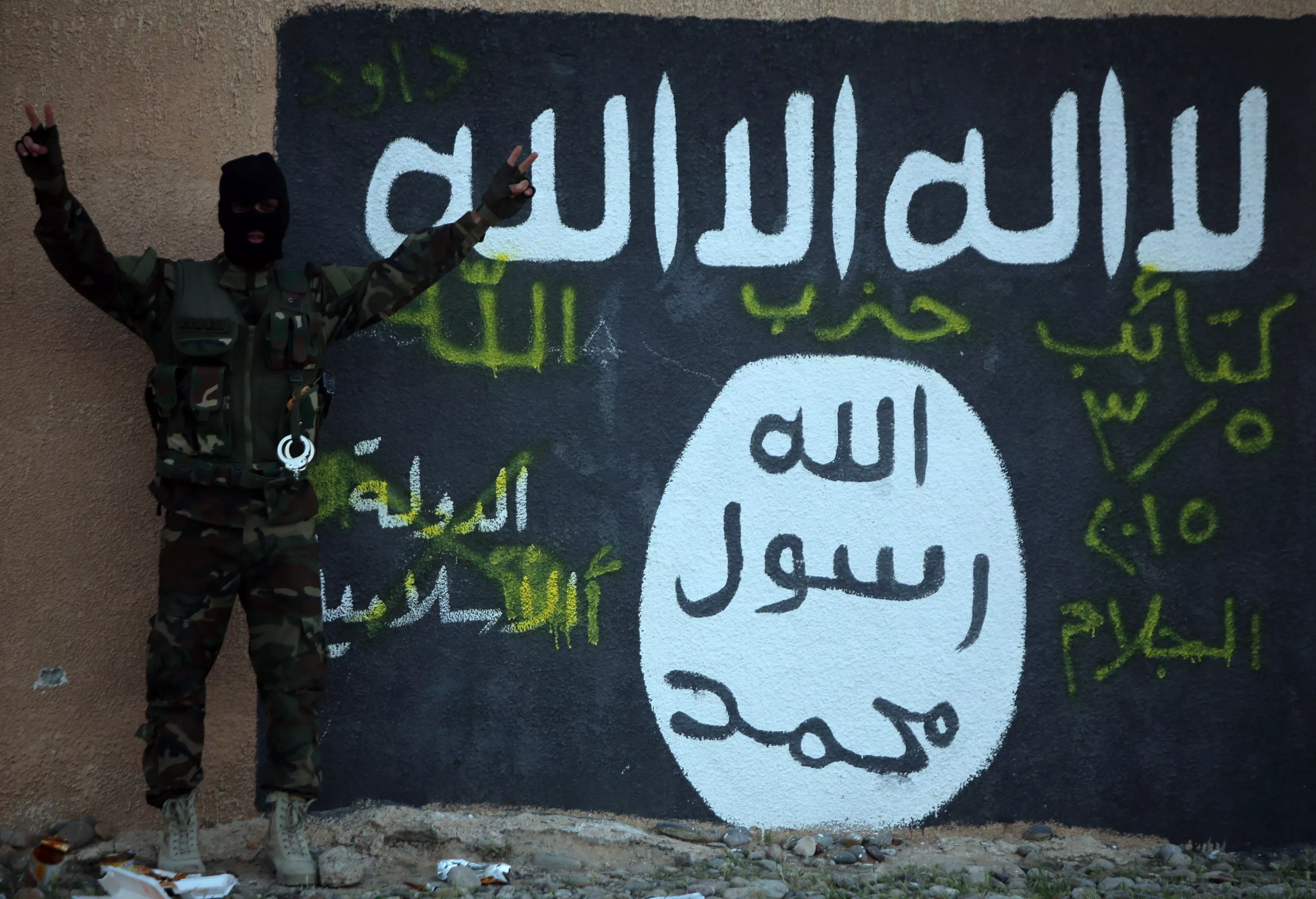 a member of the iraqi pro government forces flashes the v sign for quot victory quot as he stands in front of a mural depicting the islamic state is group 039 s flag on the outskirts of the iraqi town of ad dawr on march 6 2015 during a military operation to retake the tikrit area from jihadists some 30 000 iraqi security forces members and allied fighters launched the operation to retake tikrit on march 2 2015 the largest of its kind since is overran swathes of territory last june photo afp a member of the iraqi pro government forces flashes the v sign for quot victory quot as he stands in front of a mural depicting the islamic state is group 039 s flag on the outskirts of the iraqi town of ad dawr on march 6 2015 during a military operation to retake the tikrit area from jihadists some 30 000 iraqi security forces members and allied fighters launched the operation to retake tikrit on march 2 2015 the largest of its kind since is overran swathes of territory last june photo afp