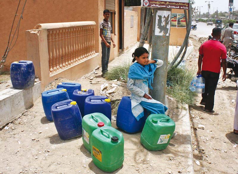 a young girl sits in the heat as she waits to fill empty cans with water in shah faisal colony the city has been facing acute water shortage for the past few weeks photo online