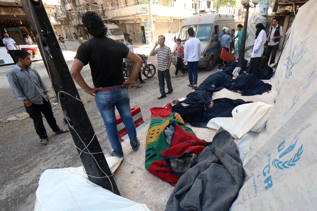 syrians stand next to the bodies of those killed in a reported bomb barrel attack by the syrian airforce on the eastern shaar neighbourhood of the northern syrian city of aleppo on may 30 2015 photo afp