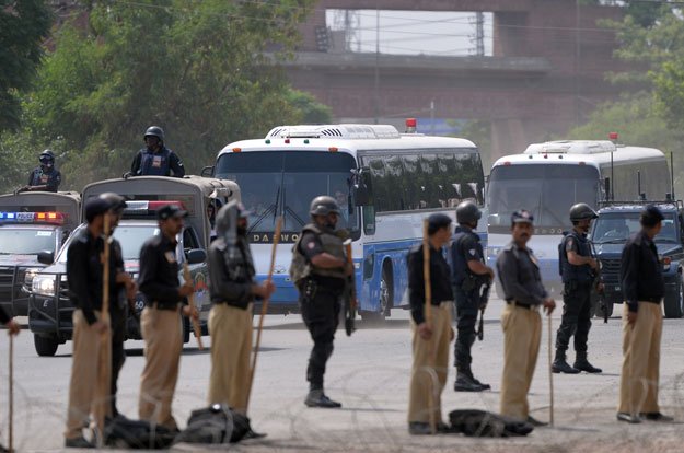 police commandos stand guard as buses carrying the zimbabwe and pakistani cricket teams arrive at the gaddafi cricket stadium in lahore on may 31 2015 photo afp