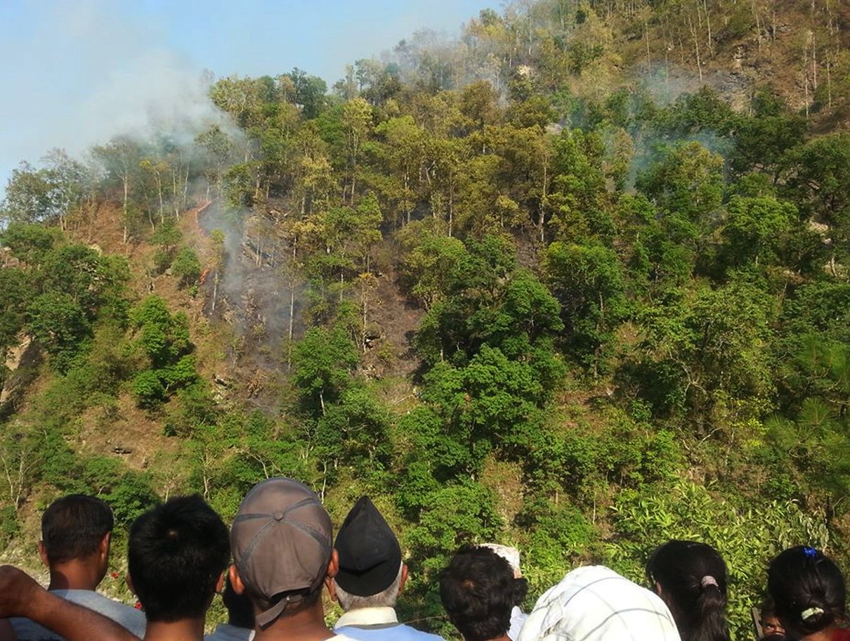 nepalese vilagers look on as smoke rises from the wreckage of a helicopter on a hillside in sindhupalchowk district some 50kms north east of kathmandu on june 2 2015 photo afp