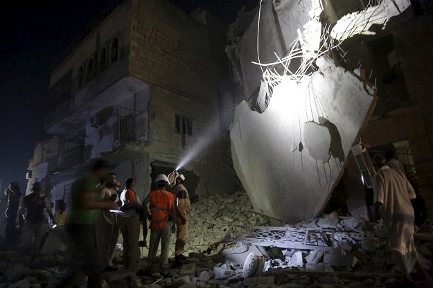 civil defense members inspect a damaged building at a site hit by what activists said was a barrel bomb dropped by forces loyal to syria 039 s president bashar al assad in maaret al naaman town in idlib province june 4 2015 photo reuters