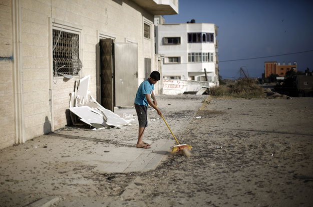 a palestinian boy cleans debris near a training base of the ezzedine al qassam brigades the military wing of hamas in gaza city after israeli warplanes struck multiple militant targets in the palestinian coastal strip on june 4 2015 in response to palestinian rocket fire photo afp