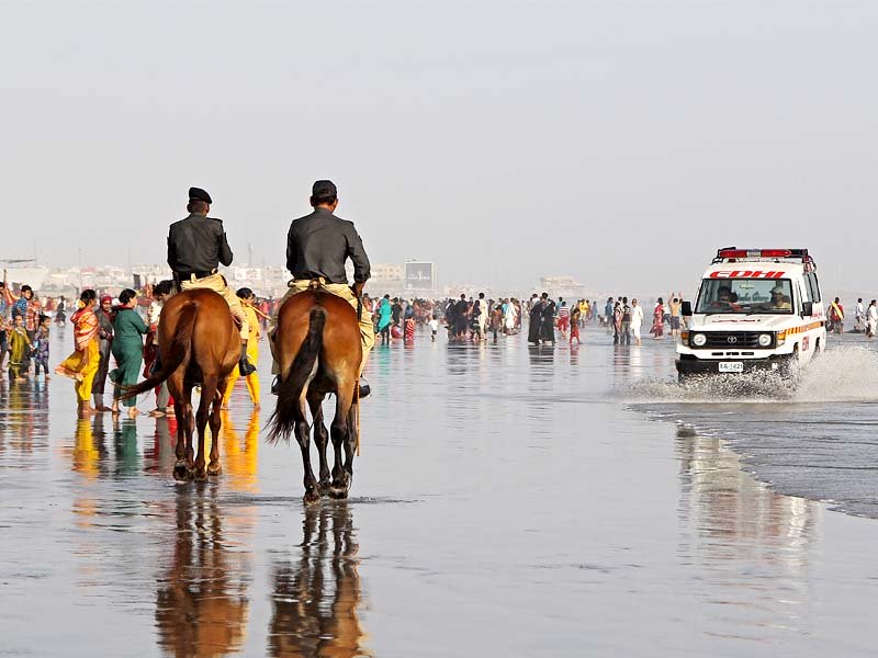 policemen patrol the beach at sea view saturday afternoon the city administration has deployed law enforcers to ensure nobody steps into the water photo aysha saleem express