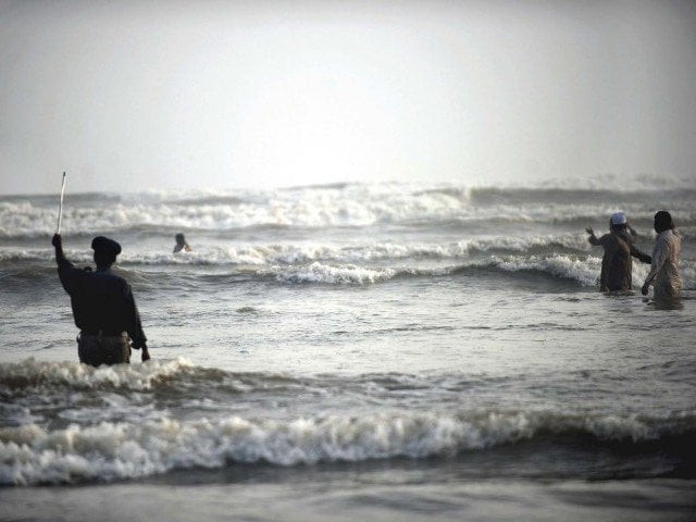 a policeman warns visitors from swimming too deep into the sea at clifton beach photo afp a policeman warns visitors from swimming too deep into the sea at clifton beach photo afp