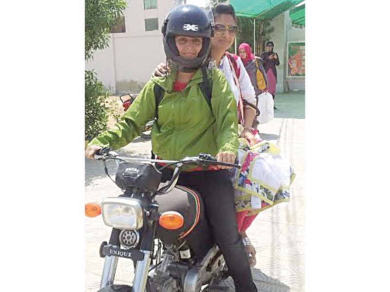 wearing a helmet 26 year old tayyaba poses on her motorcycle while her friend sits behind her she is one of the few women who ride a motorcycle against the norm in karachi photo express