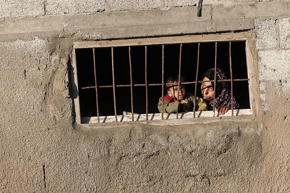 A Palestinian woman peers through the window of her house in an impoverished area in the southern Gaza Strip town of Khan Yunis. PHOTO: AFP