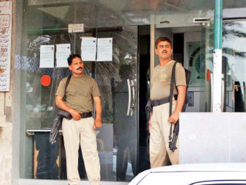 security guards stand outside the office of the sindh building control authority at civic centre after the rangers raided the office the cm has reminded the rangers that they are transgressing their authority photo file