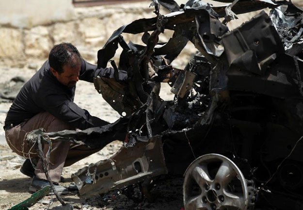 a yemeni forensic expert in sanaa on june 18 2015 inspects wreckage of a car following deadly bombings the previous day photo afp