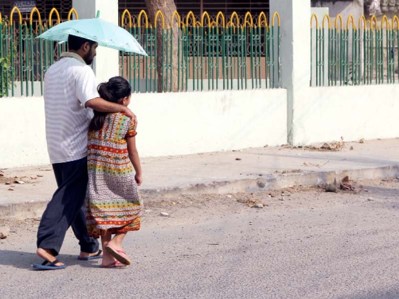 a man and a girl share an umbrella for respite from the blazing sun as the mercury soared to 44 8 degrees in karachi on saturday photo aysha saleem express