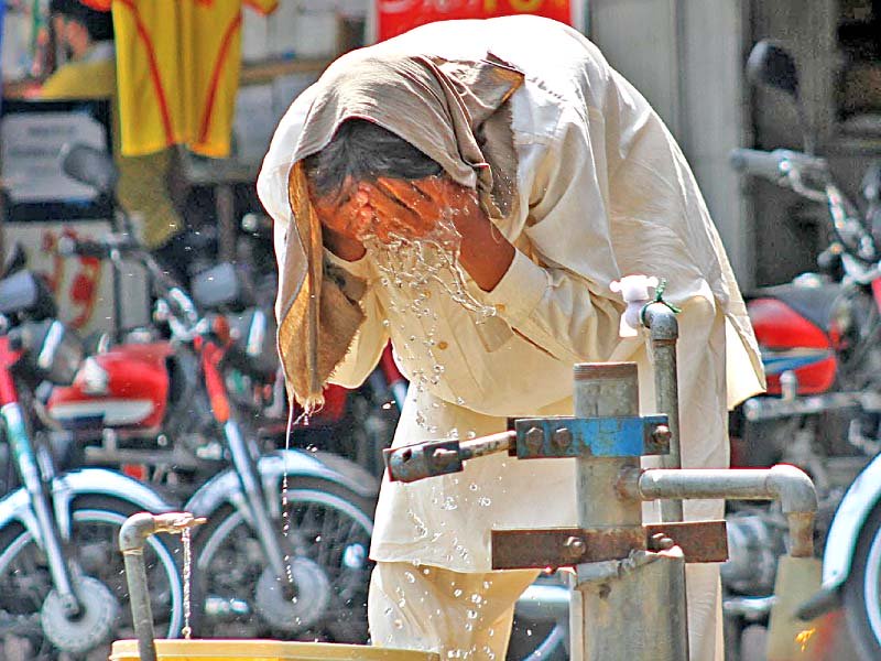 a man smears his face with water from a public tap in islamabad photo inp