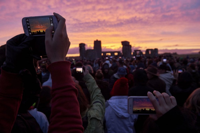 revellers photograph the sunrise as they celebrate the pagan festival of summer solstice at stonehenge in wiltshire southern england on june 21 2015 the festival which dates back thousands of years celebrates the longest day of the year when the sun is at its maximum elevation modern druids and people gather at the landmark stonehenge every year to see the sun rise on the first morning of summer photo afp