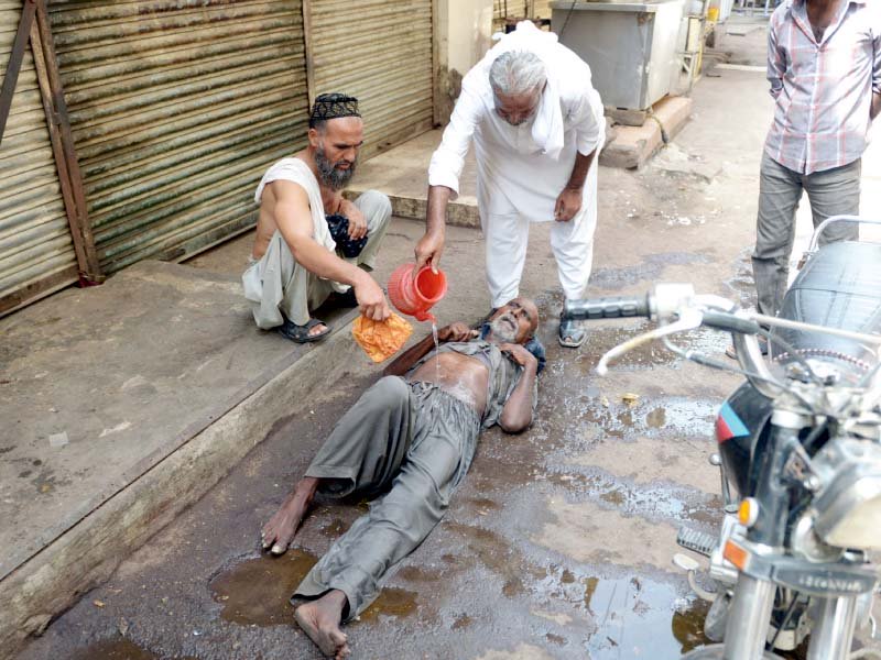 people help a heatstroke victim at a market in karachi photo afp