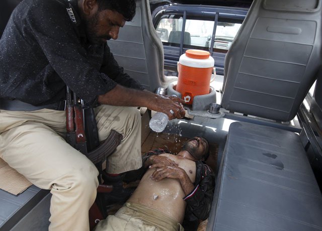 a policeman sprinkles water on a colleague who collapsed due to heat outside jpmc on wednesday photo reuters