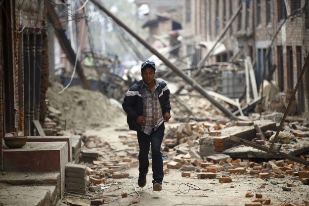 man runs past damaged houses after the earthquake struck nepal photo reuters