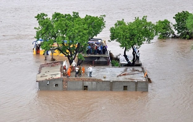 this handout photograph released by the indian ministry of defence on june 25 2015 shows indian villagers standing on a building awaiting rescue by authorities as floodwaters rise in amreli district some 200kms south west of ahmedabad in the western state of gujarat on june 24 2015 photo afp